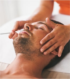 male patient lying down undergoing facial treatment in med spa from female professional