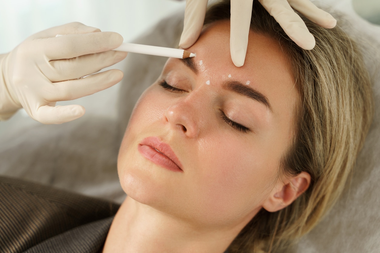 Doctor making marks on client's face before filler injection